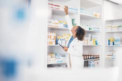 Apothekerin greift im Regal nach einem Medikament
